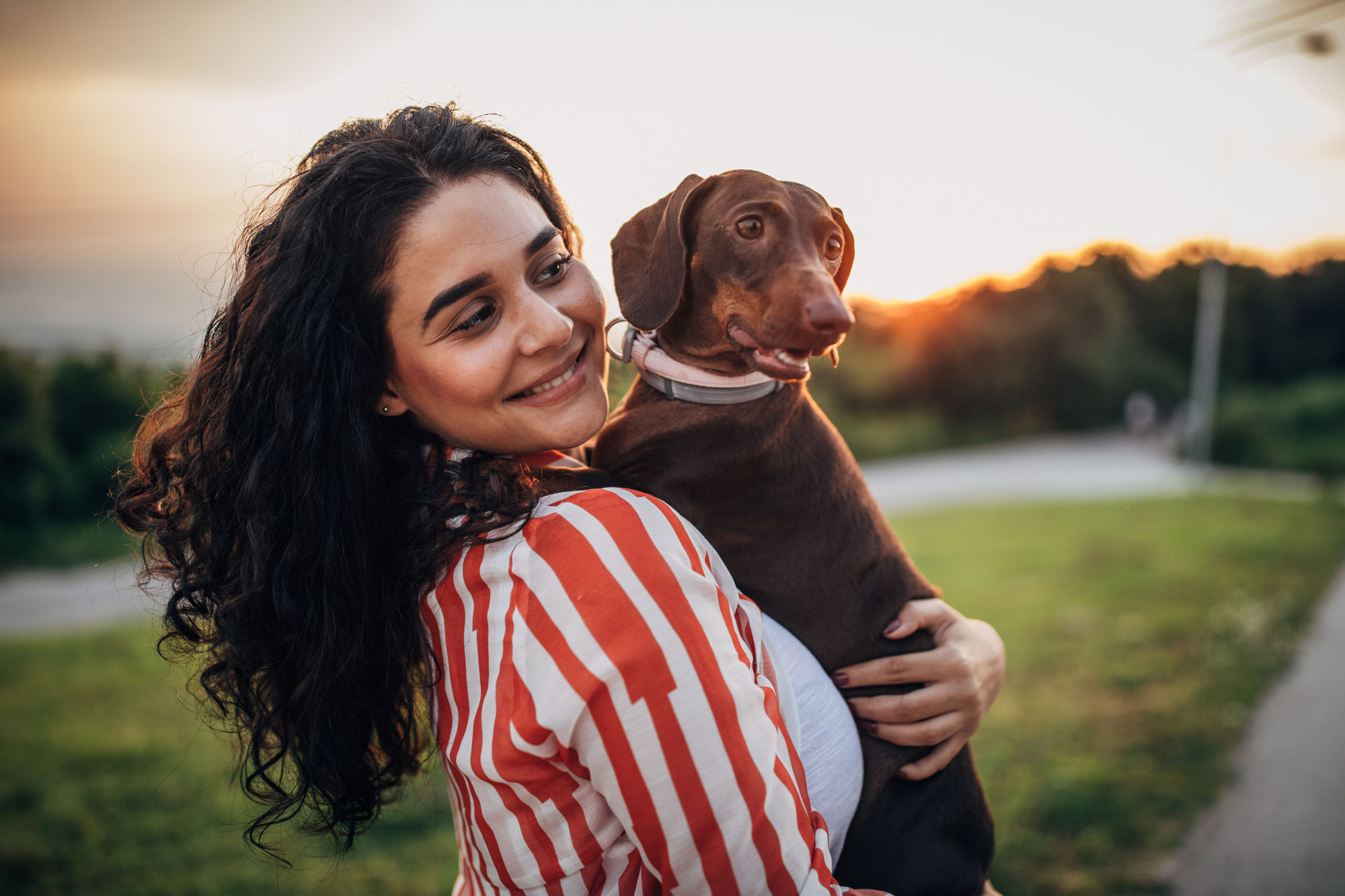 woman holding dachshund in outdoor park