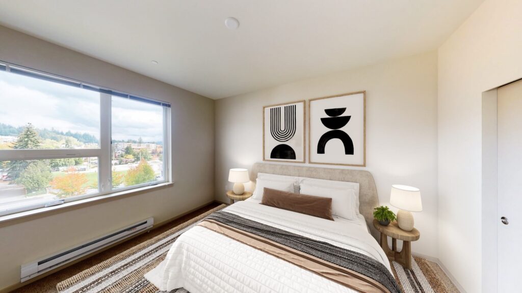 A modern bedroom with a large window, a bed with neutral bedding, two round bedside tables with lamps, abstract black-and-white artwork above the headboard, and natural light filling the room.