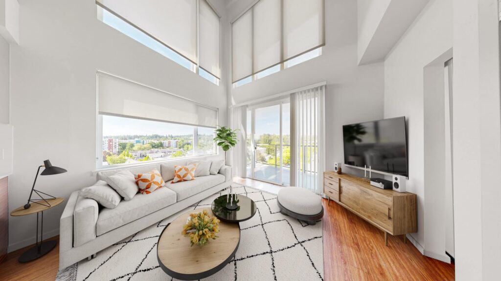 A bright, modern living room with large windows, a white sofa with orange pillows, a round coffee table, a TV on a wooden stand, hardwood floors, and a city view through the windows.